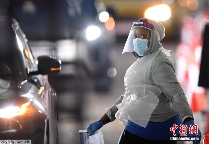 當(dāng)?shù)貢r(shí)間12月18日，英國(guó)政府公布的數(shù)據(jù)顯示，當(dāng)天英國(guó)新增奧密克戎毒株感染病例10059例。鑒于奧密克戎毒株感染病例激增，住院人數(shù)不斷上升，倫敦市長(zhǎng)宣布倫敦進(jìn)入“重大事故”狀態(tài)。圖為倫敦的一個(gè)免下車檢測(cè)中心，一名醫(yī)務(wù)工作者正準(zhǔn)備對(duì)司機(jī)進(jìn)行核酸檢測(cè)。