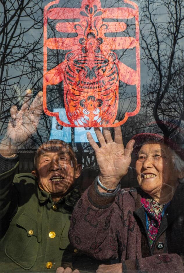 臘月里，霍州市師莊鄉(xiāng)馮南垣村村民師榮光(左)在災后重建的新家里貼窗花。(霍州市委宣傳部供圖)