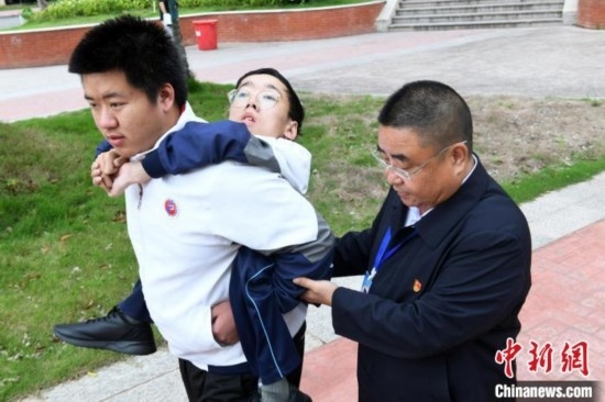 朱金祥背著鐘華強(qiáng)去教室上課的路上，也經(jīng)常碰到值班的校領(lǐng)導(dǎo)和老師前來(lái)搭把手。 卓忠偉 攝