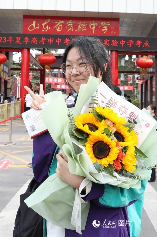6月7日高考首日，山東67萬考生走進考場，拼搏逐夢。在山東省實驗中學考點，考生進考場前手捧向日葵花拍照留念，寓意“一舉奪魁”。人民網(wǎng)記者 劉祺攝