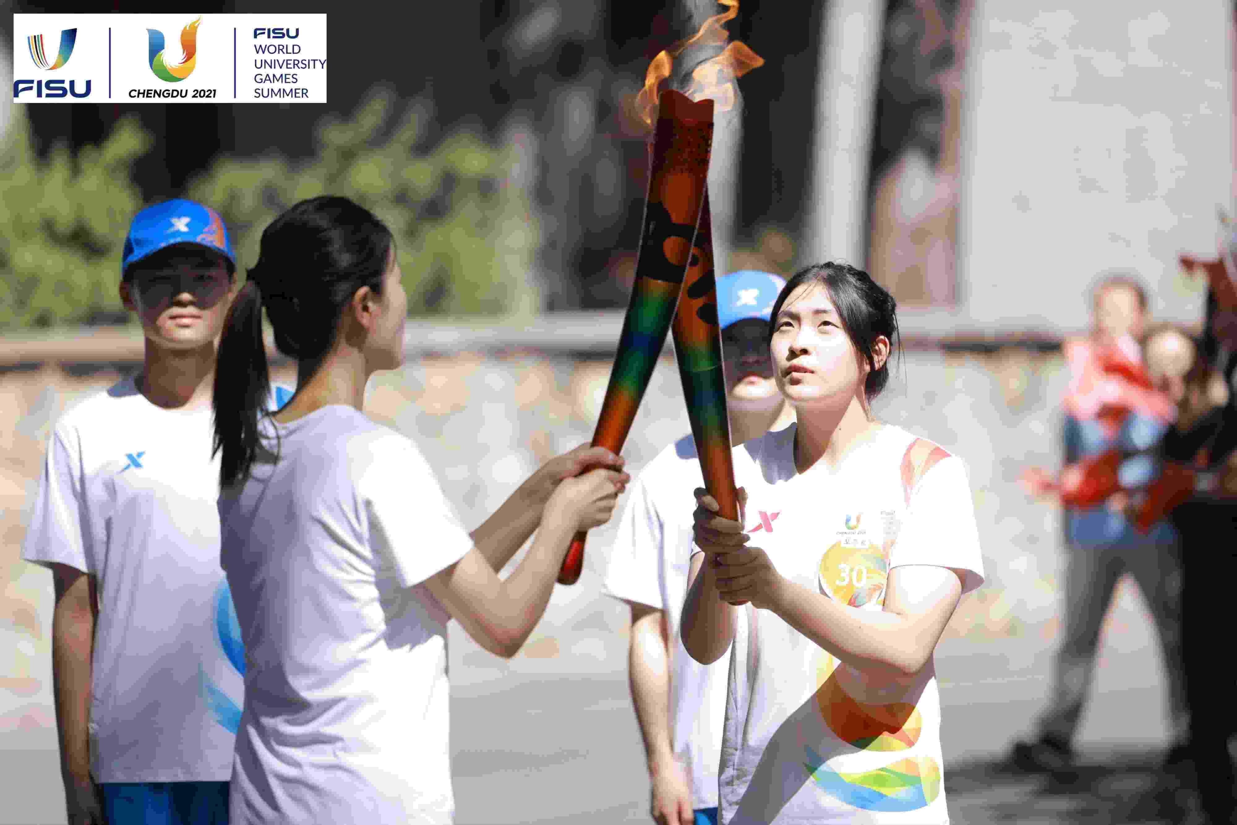 兩名大運會火炬手進行火炬?zhèn)鬟f。 圖片來源：成都大運會執(zhí)委會供圖