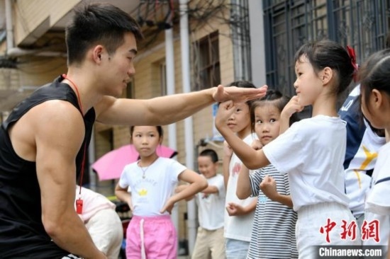 圖為大學(xué)生志愿者在組織孩子們參加體育健身活動(dòng)。廖光福 攝