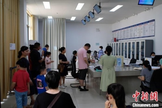 圖為在戶籍辦證廳內(nèi)排隊(duì)等待的家長(zhǎng)和孩子。劉俊聰 攝