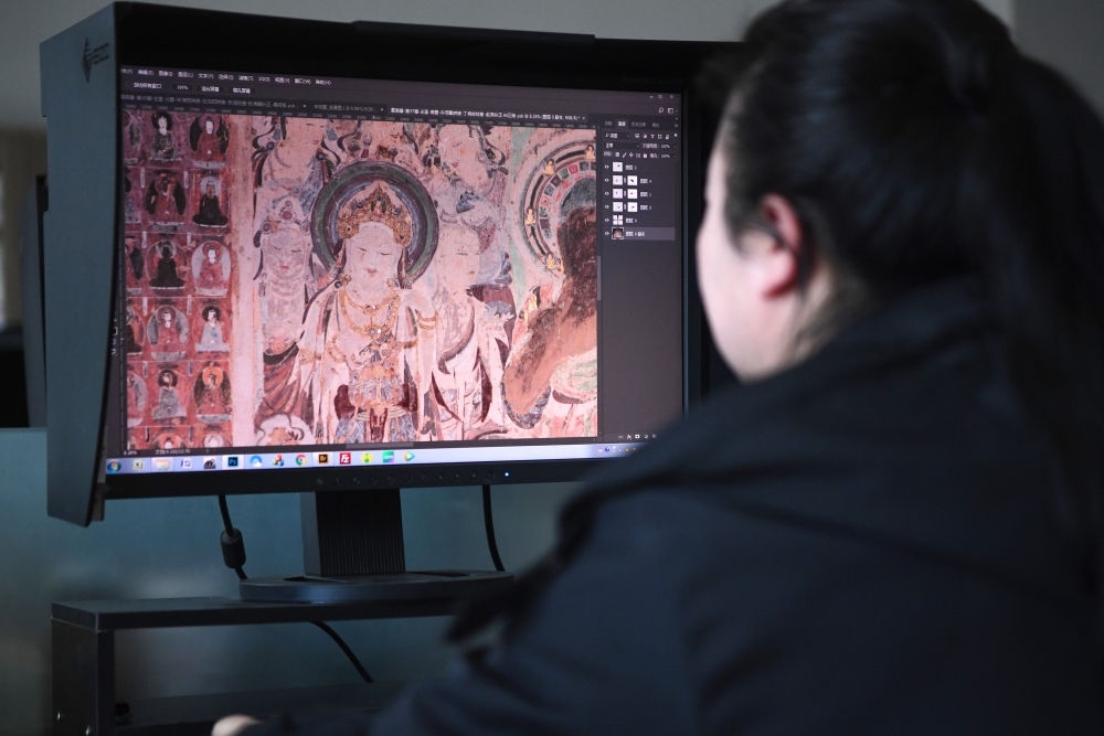 敦煌研究院文物數(shù)字化保護團隊圖像處理人員年海麗在拼接壁畫圖像（2023年4月25日攝）。數(shù)字化探索為莫高窟的保護與傳承開辟了全新路徑，數(shù)字技術(shù)讓敦煌文物走出洞窟，跨出國門，走向“永久保存、永續(xù)利用”。新華社記者 陳斌 攝