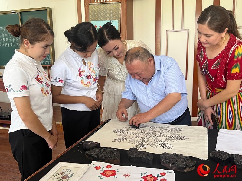 國家級非物質(zhì)文化遺產(chǎn)模戳印花布技藝傳承人吾吉阿西木?吾舒爾展示模戳印花布的制作過程。人民網(wǎng)記者 常雪梅攝