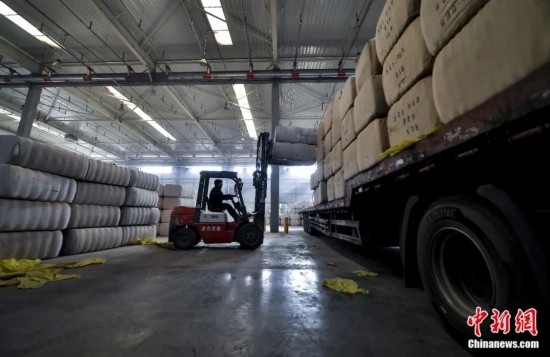 新疆喀什綜合保稅區(qū)，喀什啟路國際貿(mào)易有限公司的倉庫內(nèi)，工人正在裝載從塔吉克斯坦和烏茲別克斯坦進(jìn)口的棉花。劉新攝