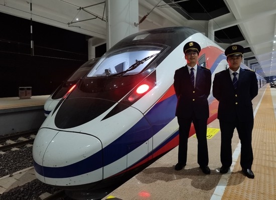 劉銀能（右一）與中國師父鄔俊鴻在動車組前合影。受訪者供圖