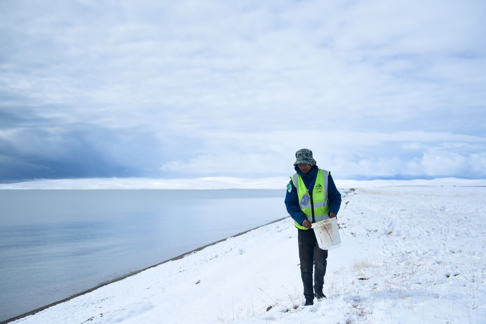 2021年10月20日，在青海省果洛藏族自治州瑪多縣扎陵湖鄉(xiāng)勒那村，三江源國家公園黃河源園區(qū)生態(tài)管護員在扎陵湖邊撿拾垃圾。新華社記者 張龍 攝
