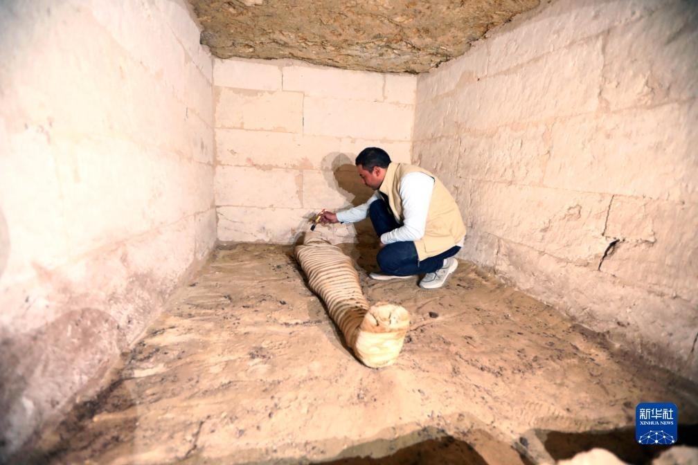 10月15日，在埃及明亞省考古現(xiàn)場(chǎng)，考古人員清理一座石鑿墓中的木乃伊。新華社發(fā)（艾哈邁德·戈馬攝）