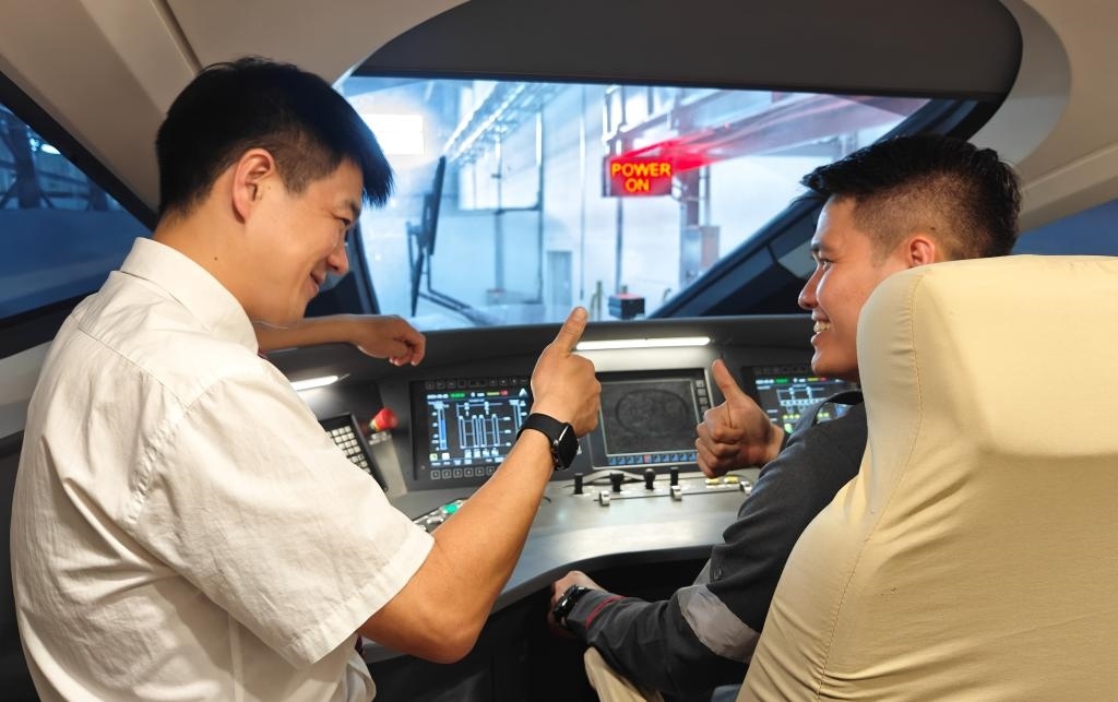 8月25日，在印度尼西亞萬隆的雅萬高鐵德卡魯爾動車所內(nèi)，中國師傅穆振（左）在向印尼火車司機塞蒂亞萬講解動車組出庫前的上電作業(yè)。