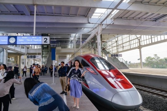  10月17日，在印度尼西亞萬(wàn)隆德卡魯爾站，乘客在站臺(tái)上和雅萬(wàn)高鐵高速動(dòng)車(chē)組列車(chē)合影。新華社記者 徐欽 攝