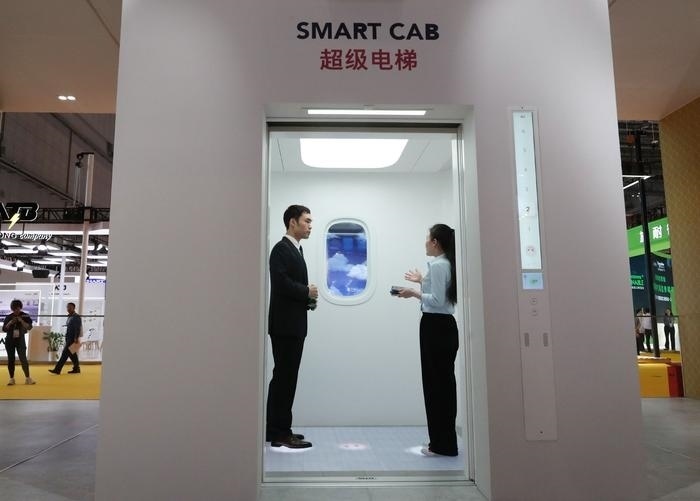 11月5日，工作人員（右）在第六屆進(jìn)博會上向參觀者介紹奧的斯公司全新推出的超級電梯。