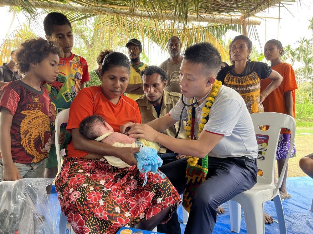 2023年8月5日，在巴布亞新幾內(nèi)亞中央省的一個(gè)村莊里，第12批援巴新中國醫(yī)療隊(duì)副隊(duì)長(zhǎng)、新生兒科副主任醫(yī)師劉振球?yàn)閶雰禾仿犜\檢查。泰樂出生時(shí)患有重癥，一度生命垂危，經(jīng)過劉振球與當(dāng)?shù)蒯t(yī)護(hù)人員的救治最終痊愈。從2002年起，中國連續(xù)向巴新派出12批醫(yī)療隊(duì)，為提高巴新醫(yī)療衛(wèi)生水平作出積極貢獻(xiàn)。
