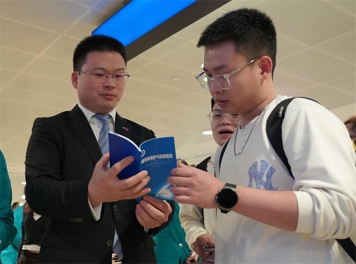 工作人員（左一）在發(fā)放《中國領事保護與協(xié)助指南》。 中國駐迪拜總領事館供圖