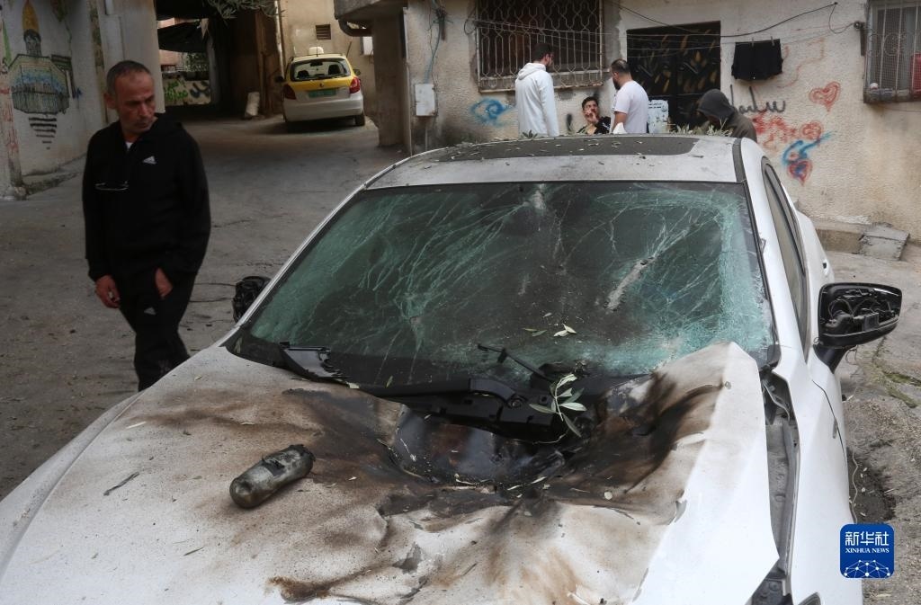12月17日，在約旦河西岸城市圖勒凱爾姆附近的一處難民營，人們查看在沖突中損毀的車輛。新華社發(fā)（尼達爾·艾仕塔耶攝）