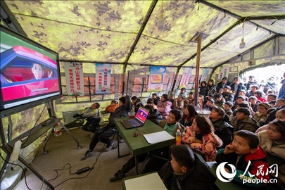 12月22日，在積石山縣大河家鎮(zhèn)大河村安置點(diǎn)，陸軍76集團(tuán)軍某旅搭建的“臨時(shí)學(xué)校”內(nèi)，小朋友正在看動(dòng)畫片。人民網(wǎng)記者 翁奇羽攝