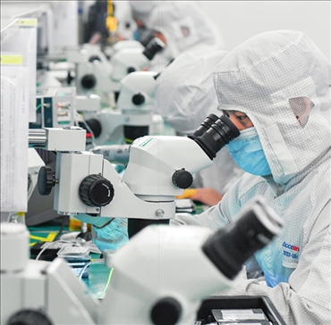 在位于武漢中國(guó)光谷的光電器件研發(fā)制造商——武漢光迅科技股份有限公司生產(chǎn)車(chē)間內(nèi)，技術(shù)人員在光模塊生產(chǎn)線作業(yè)（2023年4月11日攝）。程敏攝/本刊