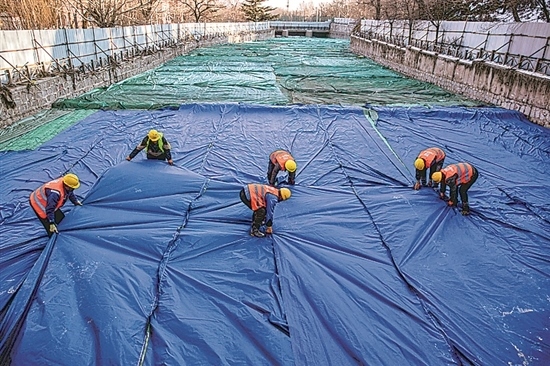 1月3日，房山區(qū)東風街道，工人正在修復的河道內(nèi)給混凝土鋪設保溫布。