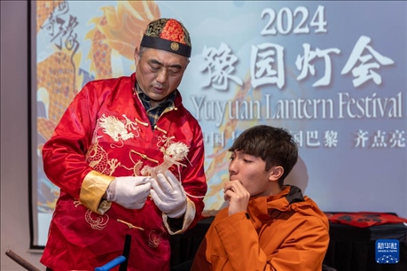 1月28日，在上海豫園舉行的民俗活動上，美國馬斯卡廷中學(xué)學(xué)生在非遺傳承人的指導(dǎo)下吹糖偶。 新華社記者 王翔 攝