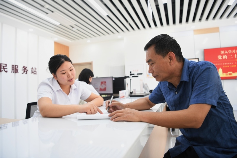 2023年5月23日，河北雄安新區(qū)容東片區(qū)南文營(yíng)社區(qū)居民（右）在社區(qū)便民服務(wù)站辦理業(yè)務(wù)。