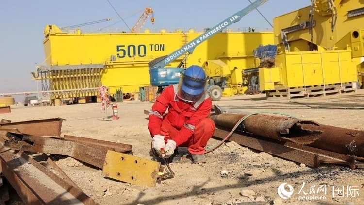 工人正在龍門吊吊裝現(xiàn)場(chǎng)切割金屬件。人民網(wǎng)記者管克江攝