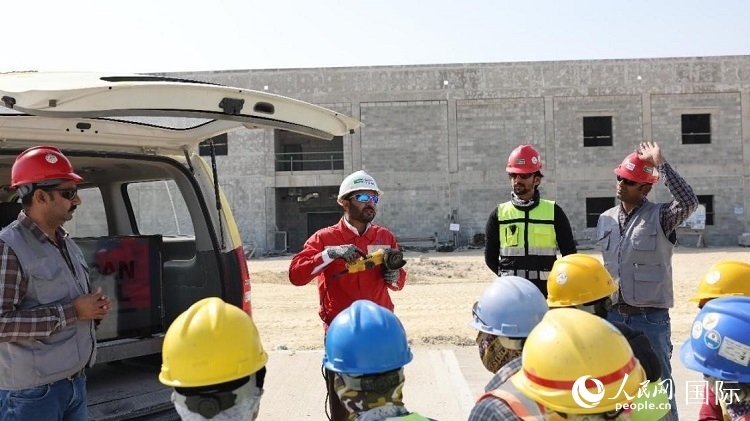 穆薩瓦爾(圖中紅衣人）現(xiàn)場(chǎng)演示工具操作規(guī)范。人民網(wǎng)記者 管克江攝