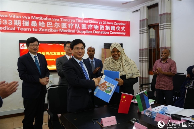 江蘇省蘇北人民醫(yī)院黨委書記束余聲與桑衛(wèi)生部首席秘書哈比巴交換捐贈(zèng)書。中國(guó)援桑醫(yī)療隊(duì)供圖