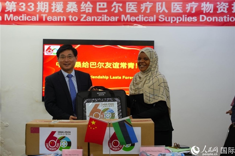 江蘇省蘇北人民醫(yī)院黨委書記束余聲捐贈(zèng)物資與桑衛(wèi)生部首席秘書哈比巴。中國(guó)援桑醫(yī)療隊(duì)供圖