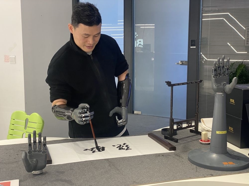 2024年3月29日，在浙江強(qiáng)腦科技有限公司展廳內(nèi)，失去雙手的產(chǎn)品體驗(yàn)官倪敏成依靠智能仿生手寫毛筆字。新華社記者 魏一駿 攝