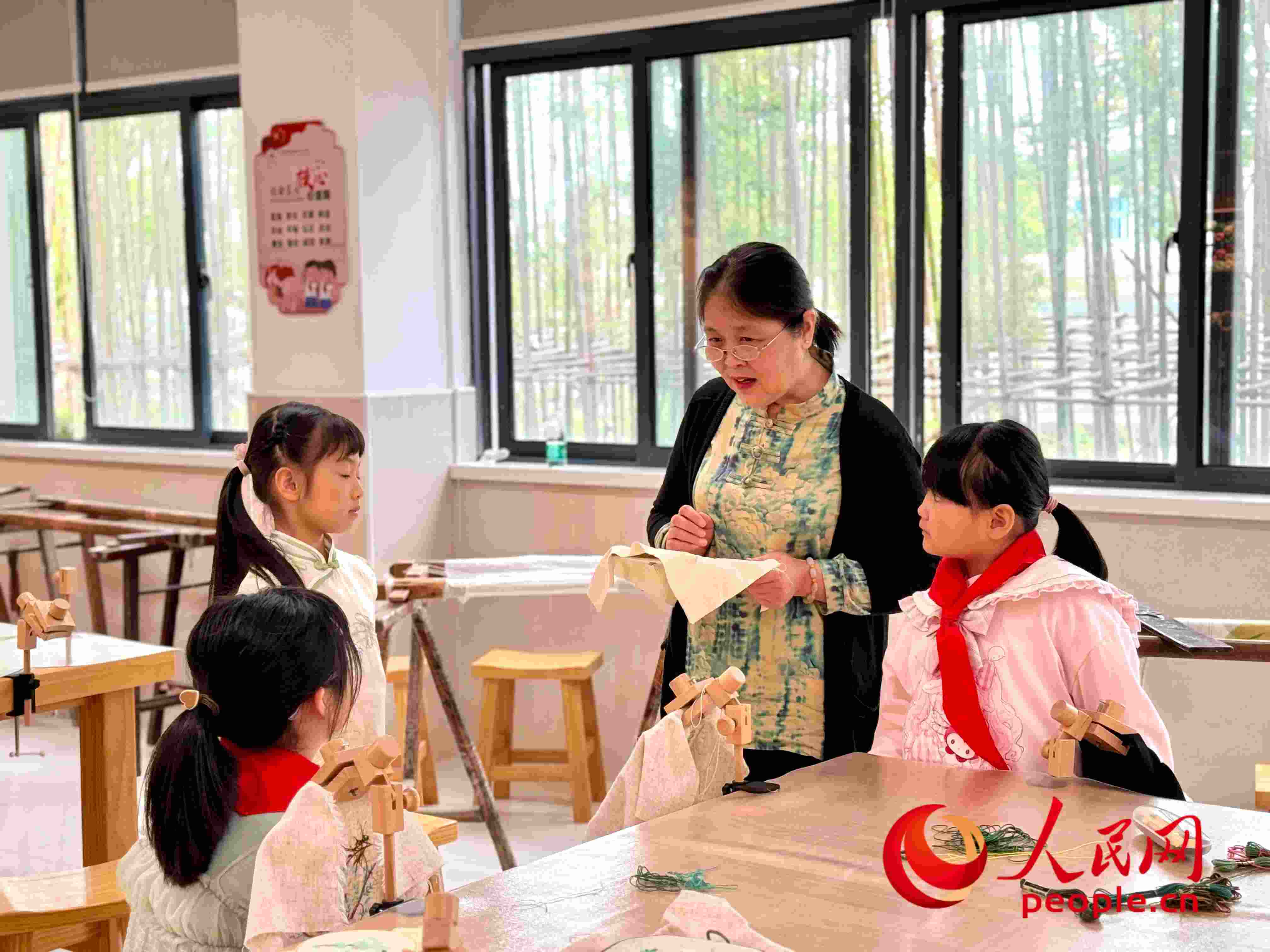 顧建珍（左三）在教孩子們刺繡知識(shí)。人民網(wǎng) 周靜圓攝