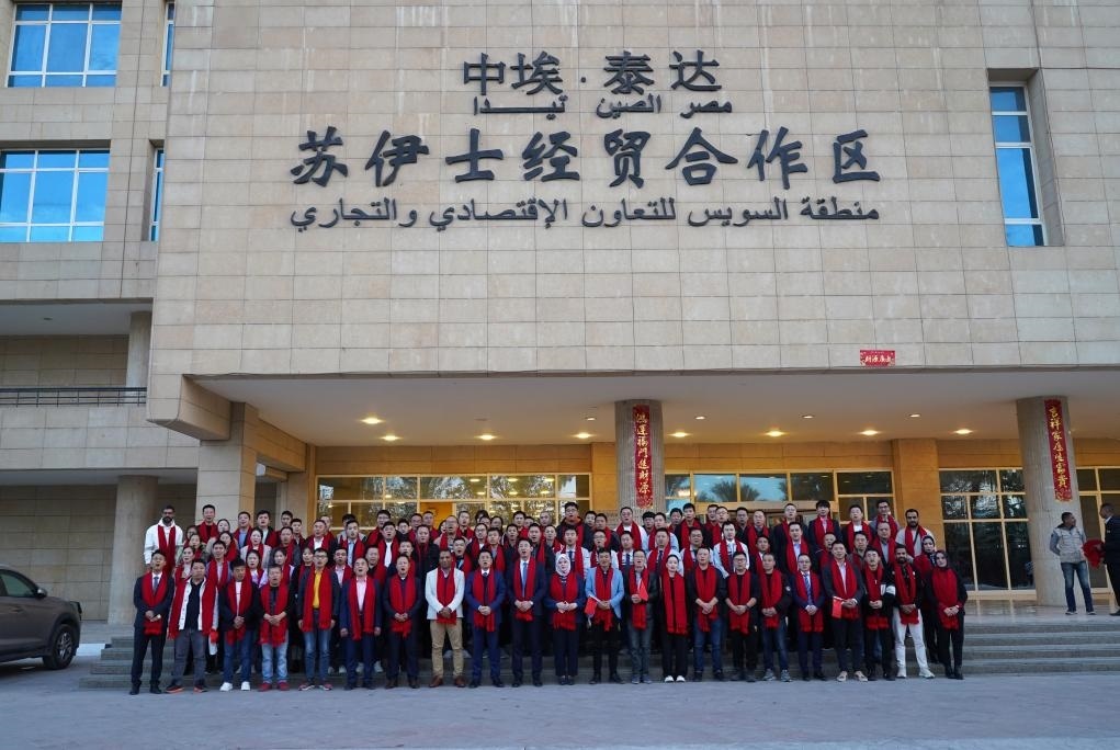 2024年2月11日，在位于埃及蘇伊士省的中?！ぬ┻_(dá)蘇伊士經(jīng)貿(mào)合作區(qū)，中埃員工在合作區(qū)辦公大樓前合影拜年。新華社發(fā)（泰達(dá)合作區(qū)供圖）
