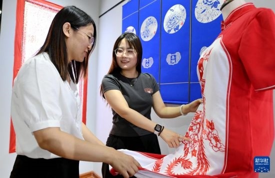 5月31日，在衡水市阜城縣一家剪紙工作室，游客在觀賞帶有剪紙?jiān)氐钠炫邸? width=