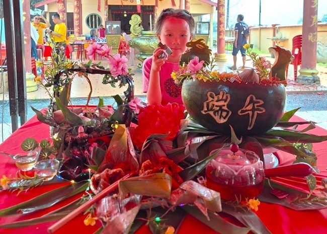 小朋友展示學(xué)裹粽子的成品照。組委會供圖