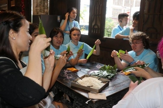 6月9日，美國青年代表在重慶永川松溉古鎮(zhèn)體驗(yàn)包粽子。新華社記者 周思宇 攝