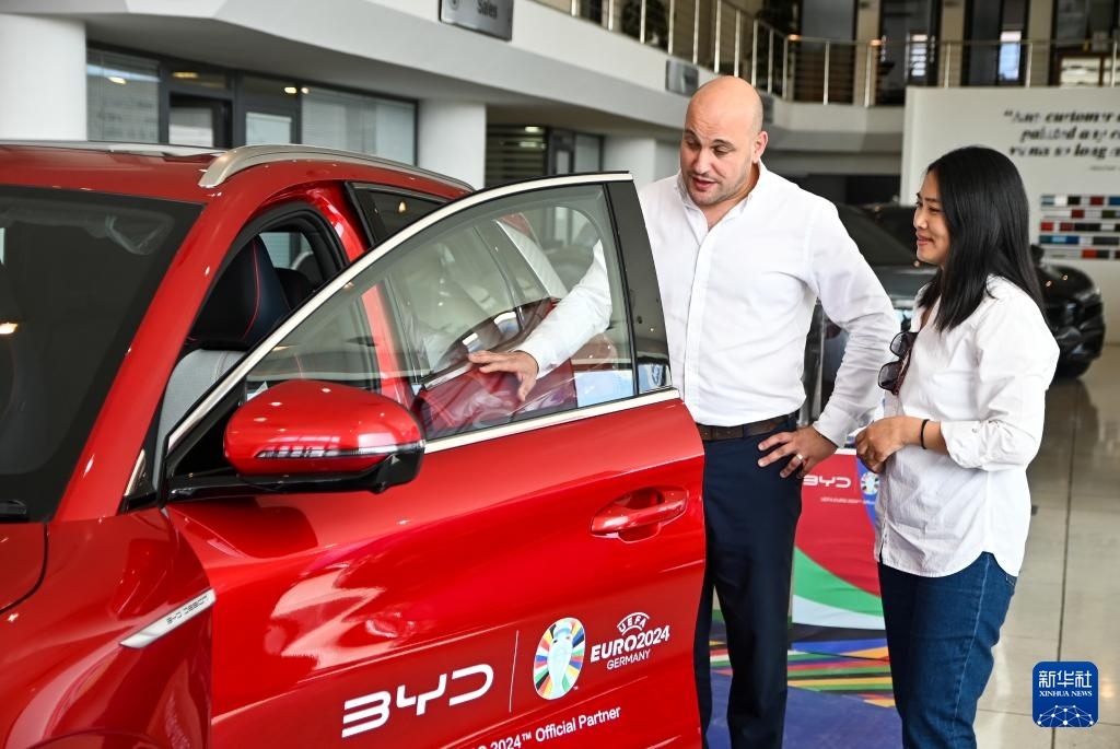 2024年5月29日，在馬耳他比爾基卡拉，馬耳他哈桑-扎米特汽車公司首席執(zhí)行官德古阿拉（左）介紹一輛比亞迪純電動汽車。新華社發(fā)（喬納森·博格 攝）