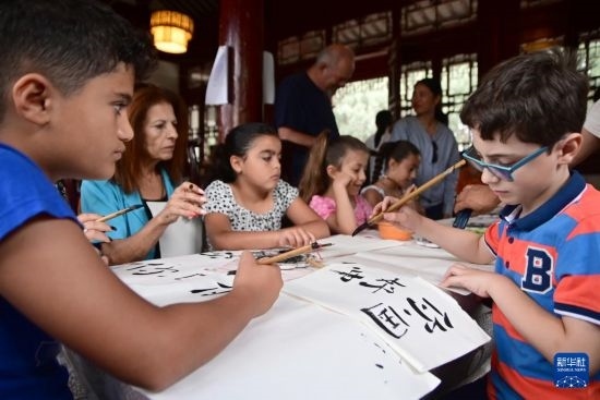 7月4日，在馬耳他桑塔露琪亞市的中國古典園林“靜園”，人們體驗中國書法。新華社發(fā)（喬納森·博格 攝）