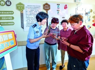 浙江湖州民警指導(dǎo)居民加入湖州“e企安”微信群，實時接收反詐信息。新華社發(fā)