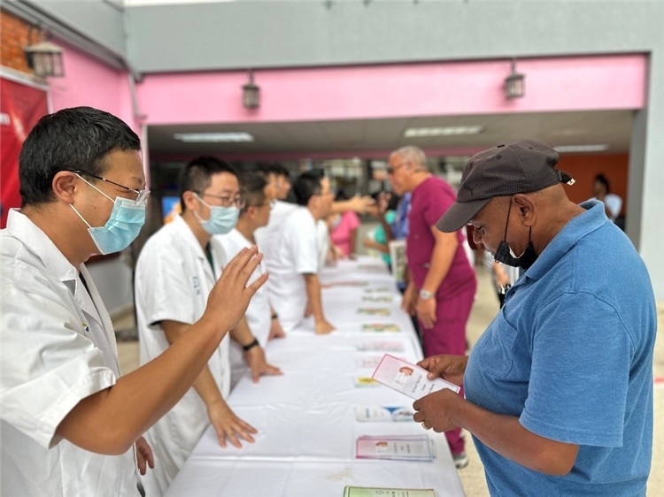 援圭醫(yī)療隊(duì)隊(duì)員們?cè)趩?dòng)儀式上為當(dāng)?shù)孛癖姺职l(fā)宣傳手冊(cè)。中國(guó)援助圭亞那醫(yī)療隊(duì)供圖