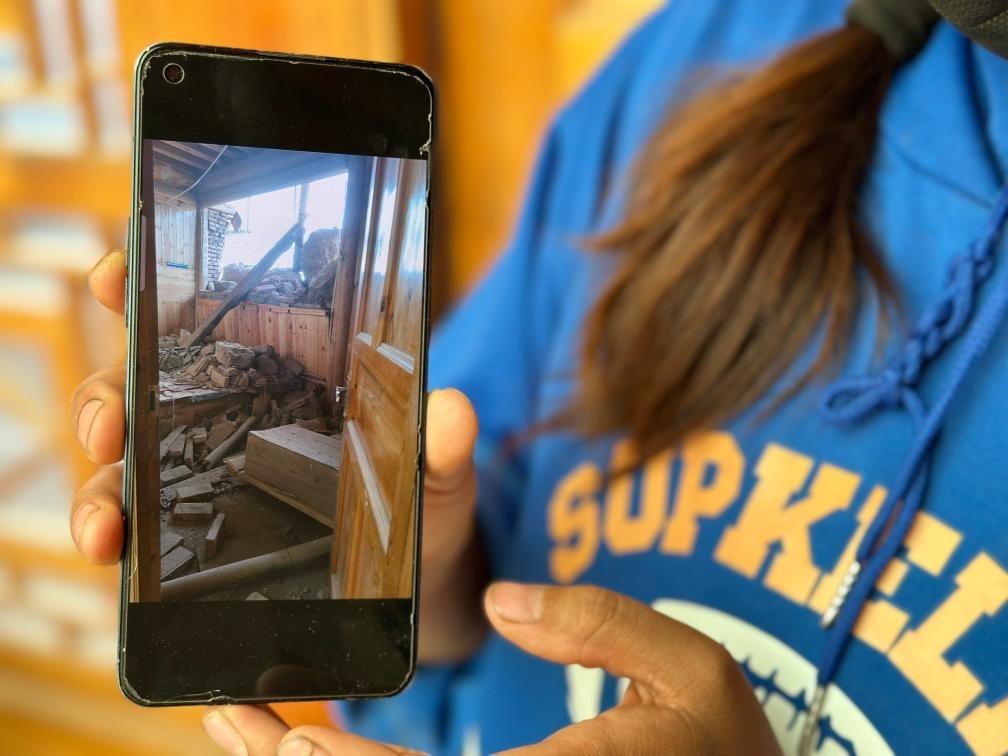 圖為7月17日拉毛東智在手機上找出地震后房屋受損的照片。新華社記者 張子琪 攝