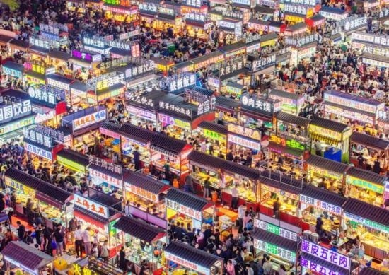 2024年4月21日，人們?cè)诤颖笔≌h小商品夜市品嘗美食（無(wú)人機(jī)照片）。新華社發(fā)（武志偉 攝）