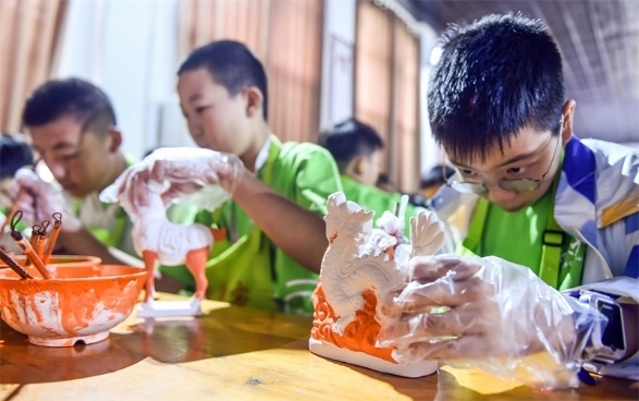 小朋友們?cè)诼尻柺忻辖騾^(qū)朝陽鎮(zhèn)南石山村體驗(yàn)唐三彩素胎施釉技藝。圖片來源：視覺中國(guó)