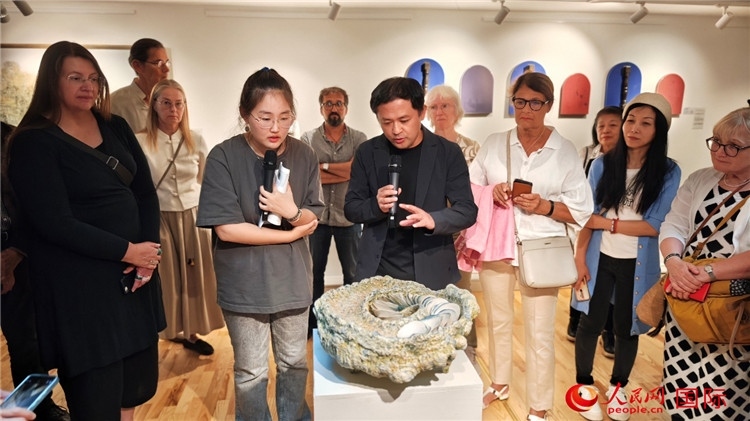 參展人、景德鎮(zhèn)陶瓷大學(xué)設(shè)計(jì)藝術(shù)學(xué)院副院長(zhǎng)余劍峰（中）向來(lái)賓介紹參展作品。人民網(wǎng)記者 殷淼攝