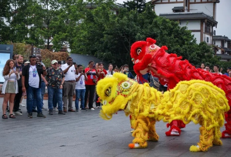 2024“一帶一路”媒體合作論壇聯(lián)合采訪調(diào)研行成員在樂山蘇稽古鎮(zhèn)觀看非遺舞獅表演。本報(bào)記者 伊霄攝