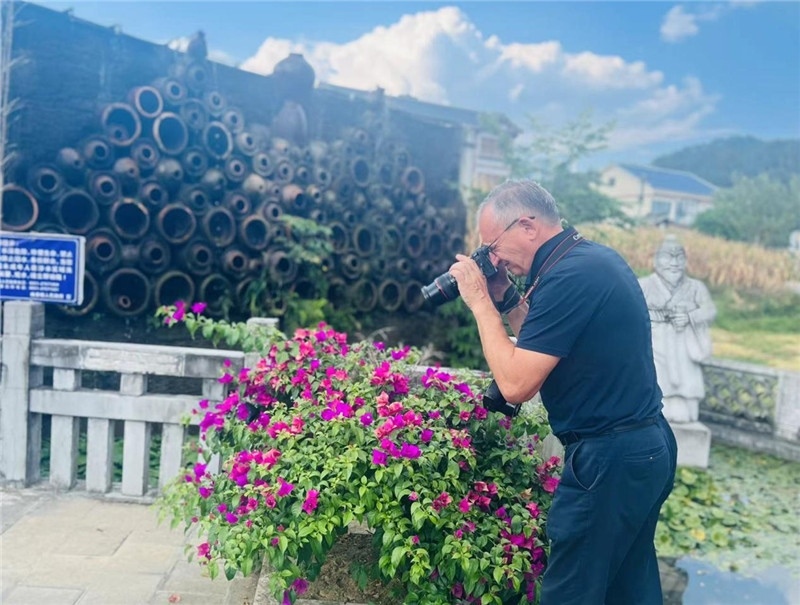 遠處黔北民居錯落有致，近處一只黑色的蝴蝶穿梭于粉紫色三角梅花叢間隙，與俄羅斯“大歐亞”總編輯弗拉基米爾·別列日內赫的鏡頭玩起了捉迷藏，“你追我逃，不亦樂乎”。（張亞欣攝）