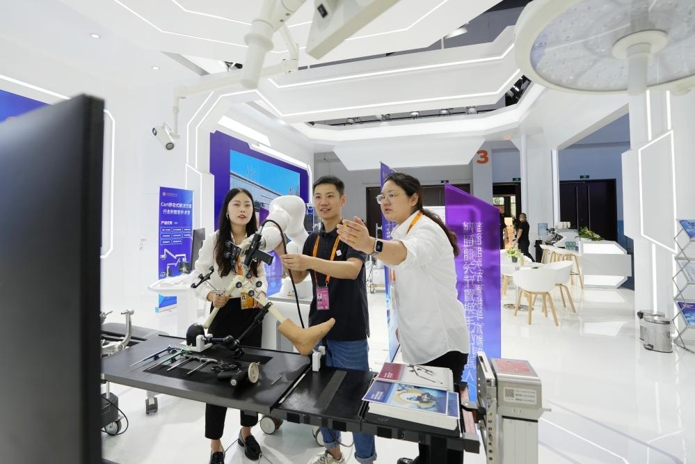 9月11日，一位媒體記者（中）在2024年服貿(mào)會國家會議中心會場體驗北京納通科技集團有限公司的膝關(guān)節(jié)置換手術(shù)機器人。新華社記者鞠煥宗 攝