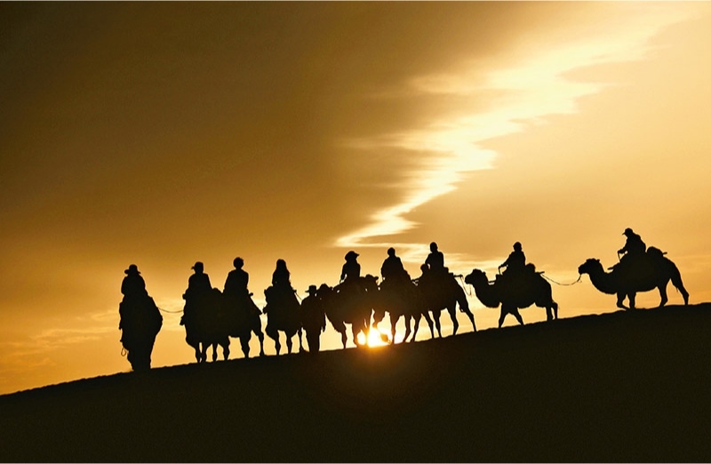 新時代以來，文化和旅游深度融合發(fā)展體制機制不斷健全，成功走出了一條獨具特色的中國旅游發(fā)展之路。圖為2024年9月1日清晨，游客在甘肅省敦煌市鳴沙山月牙泉景區(qū)乘騎駱駝，欣賞大漠風光，體驗絲路風情。 新華社發(fā) 張曉亮/攝