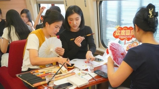10月1日，旅客們?cè)贕1634次列車上給油紙傘作畫。新華社記者周義 攝