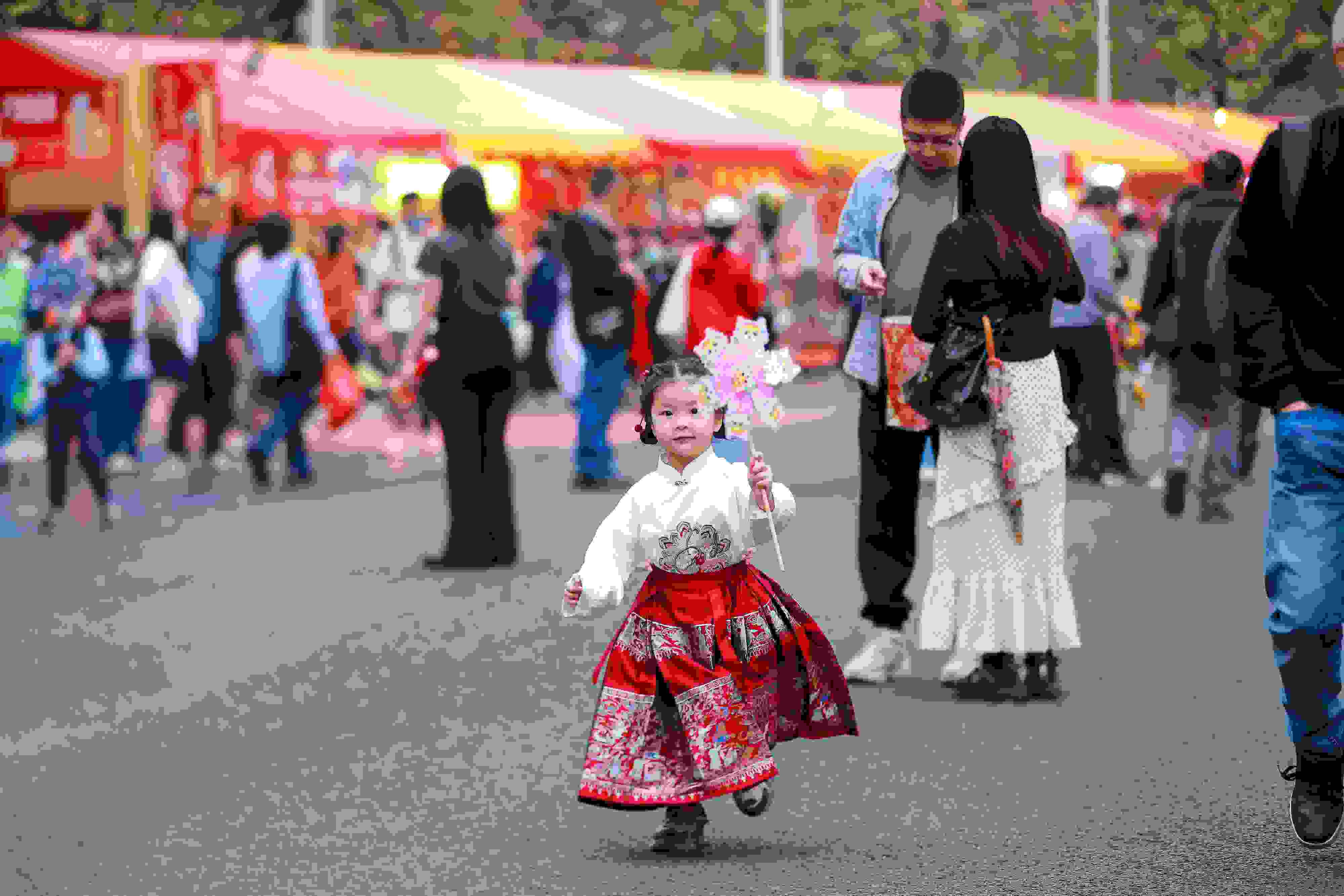 拿著風(fēng)車穿著馬面裙的小女孩在廣州的花市上開心奔跑。