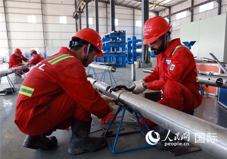 中伊員工共同在檢修鉆井設(shè)備。人民網(wǎng)記者管克江攝