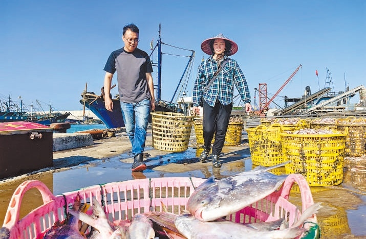 許小斌（左）和漁民一起搬運(yùn)海鮮。本報(bào)記者 付 文攝